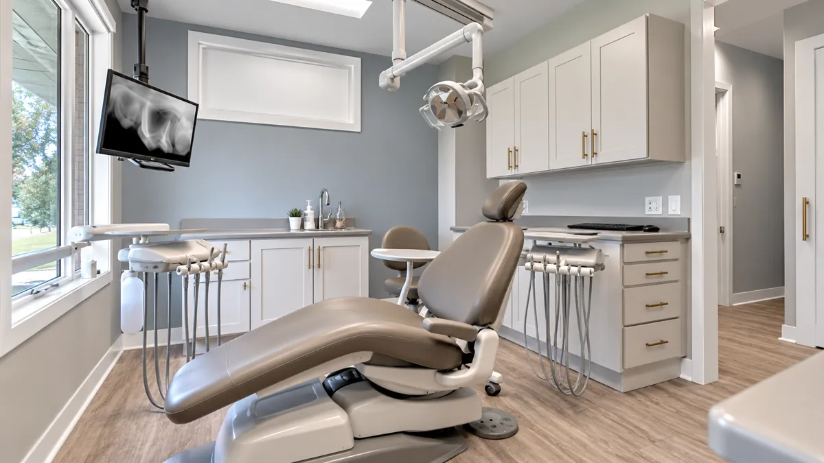 Bright treatment room with a blue accent wall, ceiling-mounted X-ray monitor and a reclined chair